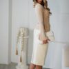 Woman in beige top and white skirt.