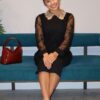 A woman in black dress sitting on blue bench.